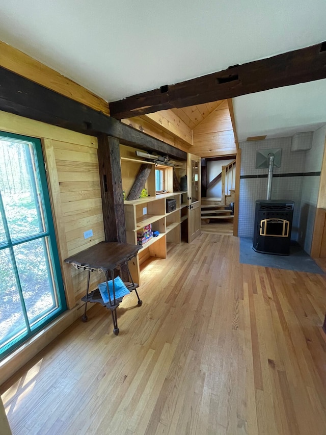 living area with light wood-style floors, plenty of natural light, a wood stove, wooden walls, and heating unit