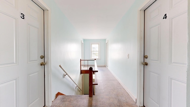 hallway with an upstairs landing and baseboards