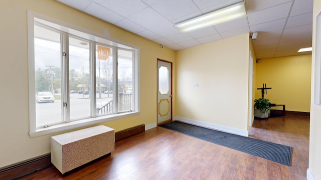 foyer with dark wood-type flooring, a paneled ceiling, a baseboard heating unit, and baseboards