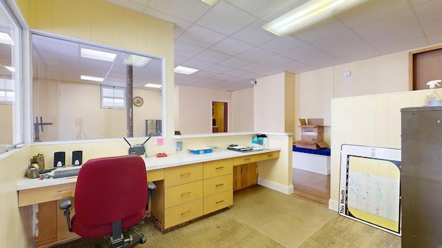 office area with built in study area and a paneled ceiling