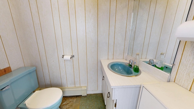 half bath featuring toilet, a baseboard radiator, vanity, and wood walls