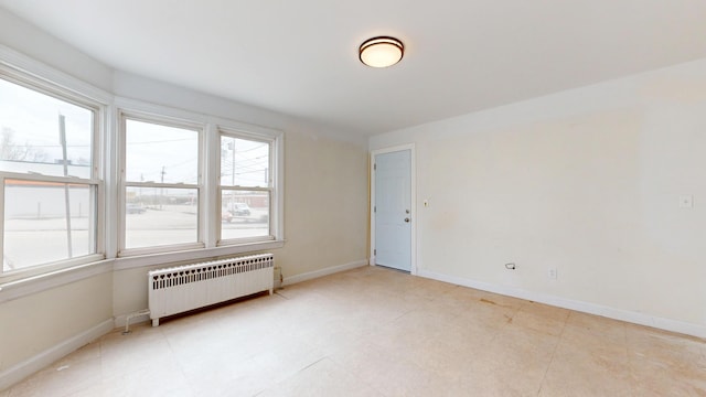 unfurnished room featuring radiator and baseboards