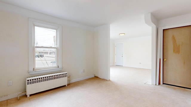 empty room featuring radiator heating unit, plenty of natural light, and baseboards
