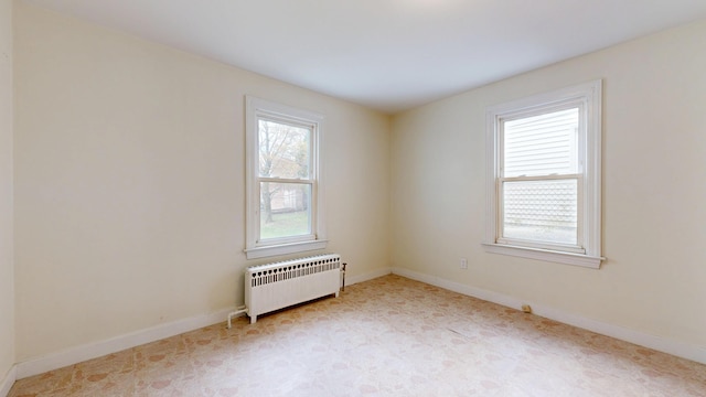 unfurnished room featuring radiator and baseboards