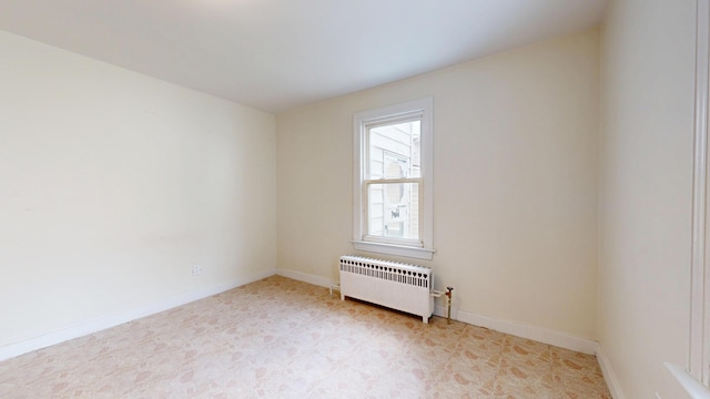 spare room with radiator heating unit, baseboards, and light flooring