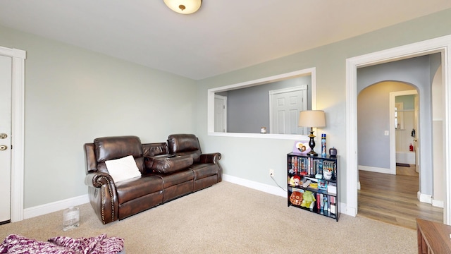 living room with arched walkways, carpet, and baseboards