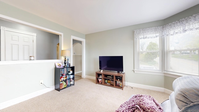 carpeted living room with baseboards and arched walkways