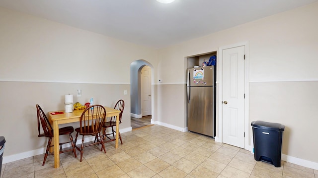 dining room featuring arched walkways and baseboards