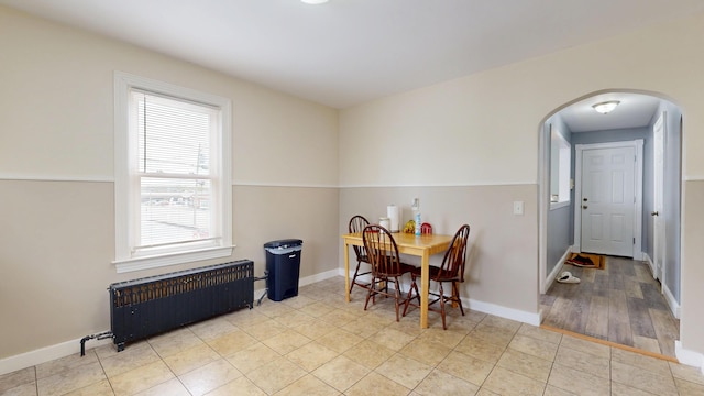 dining space featuring radiator, arched walkways, baseboards, and tile patterned floors