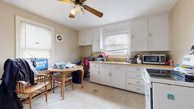 kitchen featuring stainless steel microwave, electric stove, white cabinetry, a sink, and ceiling fan