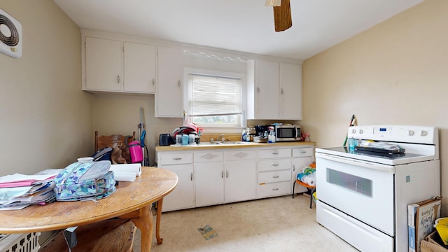 kitchen featuring electric range, stainless steel microwave, white cabinetry, and light countertops