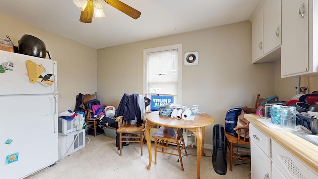 dining area with ceiling fan and light carpet