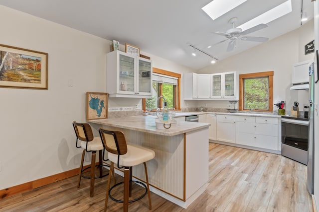 186 Ridge Rd, Frye Island, ME 04071 - kitchen featuring a skylight, appliances with stainless steel finishes, a peninsula, under cabinet range hood, and lofted ceiling