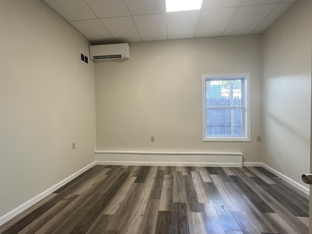 10 W Bates St, Auburn, ME 04210 - unfurnished room featuring a wall unit AC, dark wood-style flooring, baseboards, and a drop ceiling