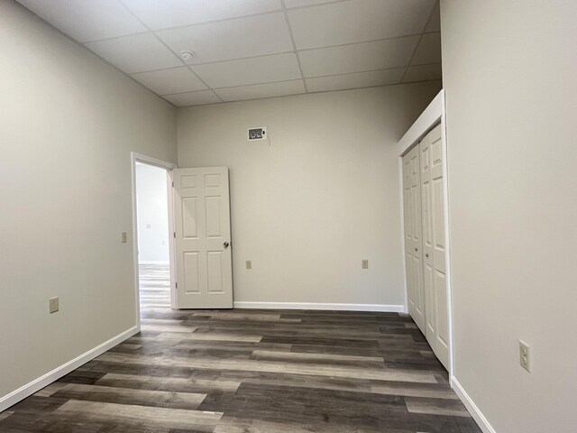 10 W Bates St, Auburn, ME 04210 - empty room featuring a drop ceiling, dark wood-style floors, and baseboards