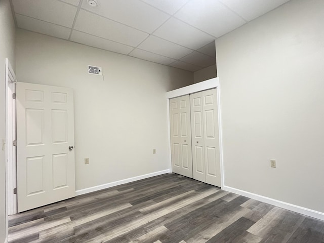 10 W Bates St, Auburn, ME 04210 - unfurnished bedroom featuring a drop ceiling, a closet, dark wood-style flooring, and baseboards