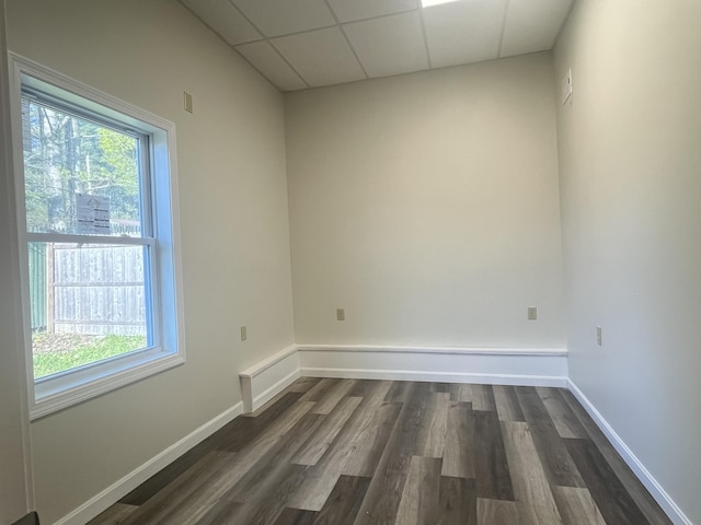 10 W Bates St, Auburn, ME 04210 - empty room featuring dark wood-type flooring, plenty of natural light, a drop ceiling, and baseboards