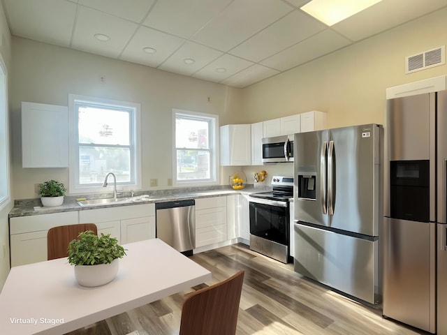 10 W Bates St, Auburn, ME 04210 - kitchen with appliances with stainless steel finishes, a sink, a drop ceiling, white cabinets, and wood finished floors