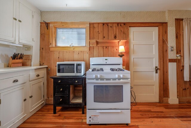 6 Sea St, Northeast Harbor, Mount Desert, ME 04662 - kitchen with white gas range oven, light wood-style flooring, white cabinets, wooden walls, and light countertops