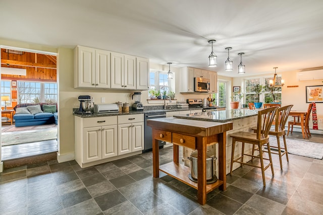 kitchen featuring stainless steel appliances, a wall unit AC, a sink, and decorative light fixtures