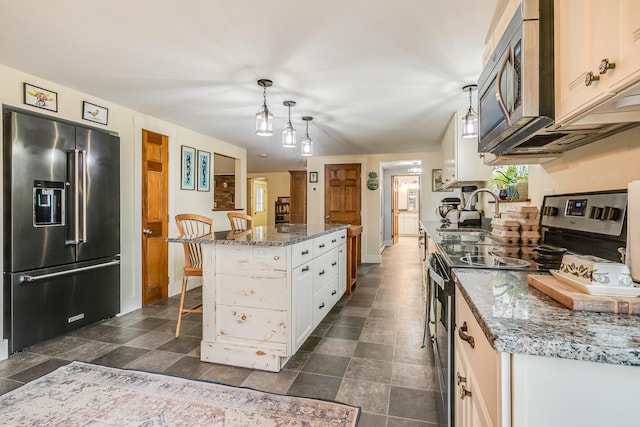 kitchen featuring appliances with stainless steel finishes, a center island, a sink, a kitchen breakfast bar, and white cabinets