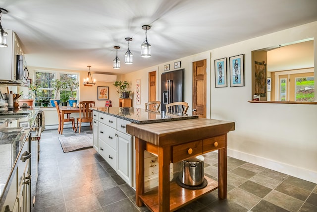 kitchen featuring high quality fridge, stainless steel microwave, white cabinets, and dark stone counters