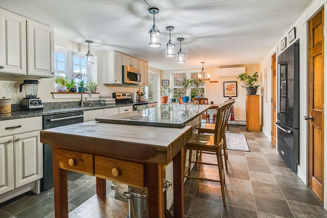 kitchen featuring appliances with stainless steel finishes, a wall mounted air conditioner, a sink, and pendant lighting
