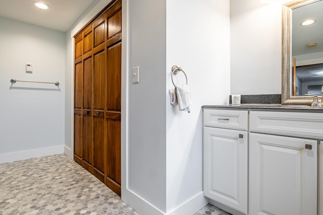 bathroom featuring baseboards, recessed lighting, and vanity
