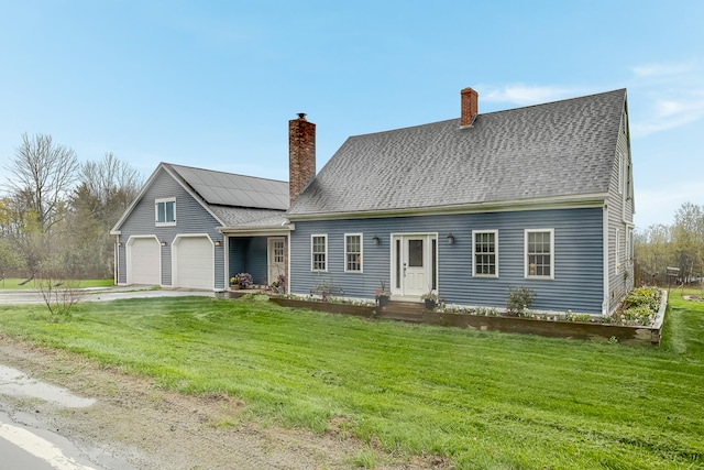 new england style home with a chimney, a garage, a front lawn, and solar panels