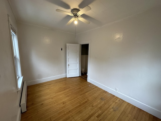 91 Elm St, Millinocket, ME 04462 - spare room featuring baseboard heating, baseboards, hardwood / wood-style flooring, ceiling fan, and ornamental molding