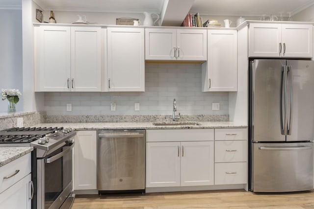 25 Preservation Ln Unit 9, South Portland, ME 04106 - kitchen featuring stainless steel appliances, a sink, white cabinets, decorative backsplash, and ornamental molding