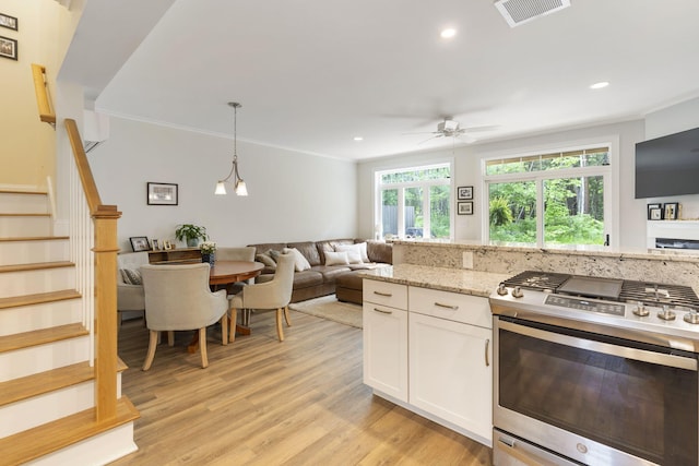 25 Preservation Ln Unit 9, South Portland, ME 04106 - kitchen with gas range, white cabinetry, a ceiling fan, open floor plan, and light stone counters