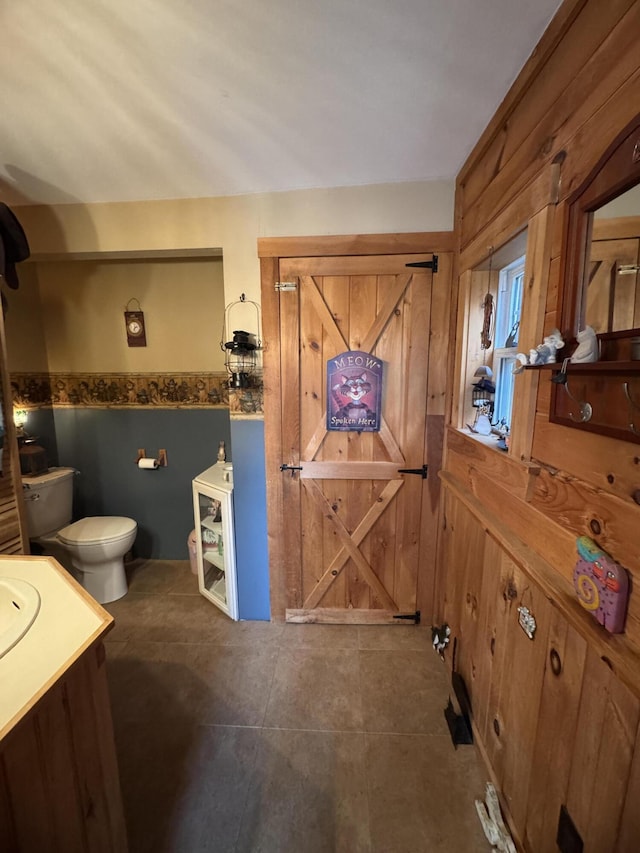 7 Howard Siding Ln, Abbot, ME 04406 - bathroom featuring toilet, vanity, wood walls, and tile patterned flooring