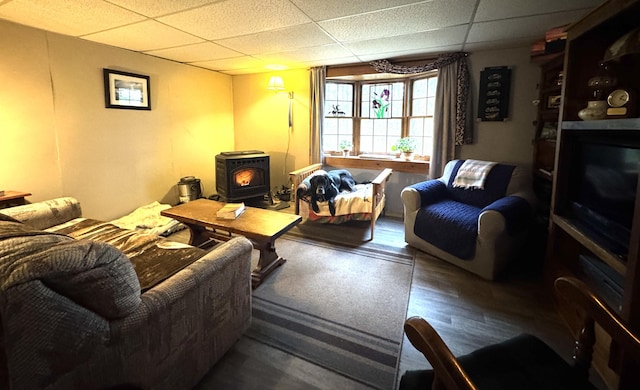 7 Howard Siding Ln, Abbot, ME 04406 - living room featuring a wood stove, a paneled ceiling, and wood finished floors