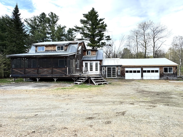 7 Howard Siding Ln, Abbot, ME 04406 - view of front of property with a wooden deck, metal roof, dirt driveway, a garage, and a sunroom