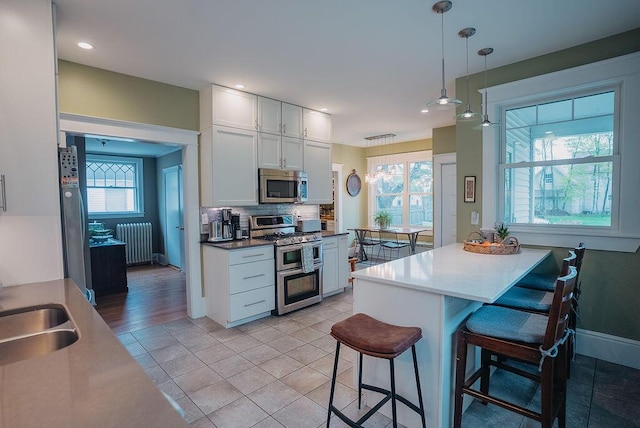 107 Maple St, Bangor, ME 04401 - kitchen with appliances with stainless steel finishes, radiator, a kitchen bar, white cabinets, and tasteful backsplash