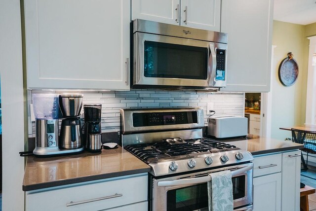 107 Maple St, Bangor, ME 04401 - kitchen with stainless steel appliances, tasteful backsplash, white cabinets, and dark countertops