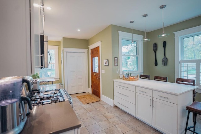 107 Maple St, Bangor, ME 04401 - kitchen with white cabinets, light tile patterned flooring, pendant lighting, gas stove, and baseboards