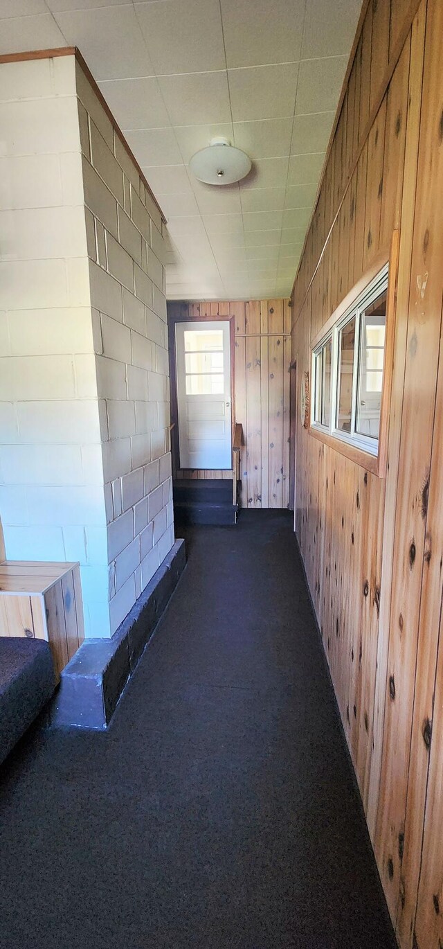 corridor with dark carpet and wood walls