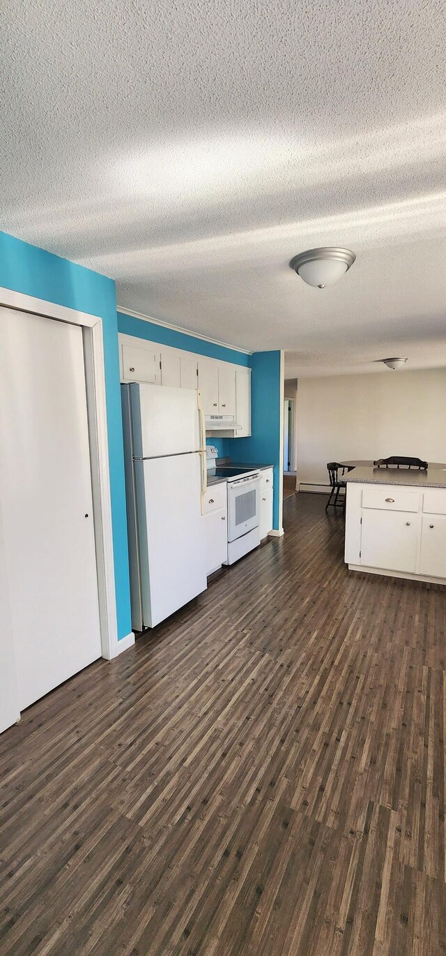 kitchen featuring white appliances, under cabinet range hood, white cabinets, dark wood-style floors, and a textured ceiling