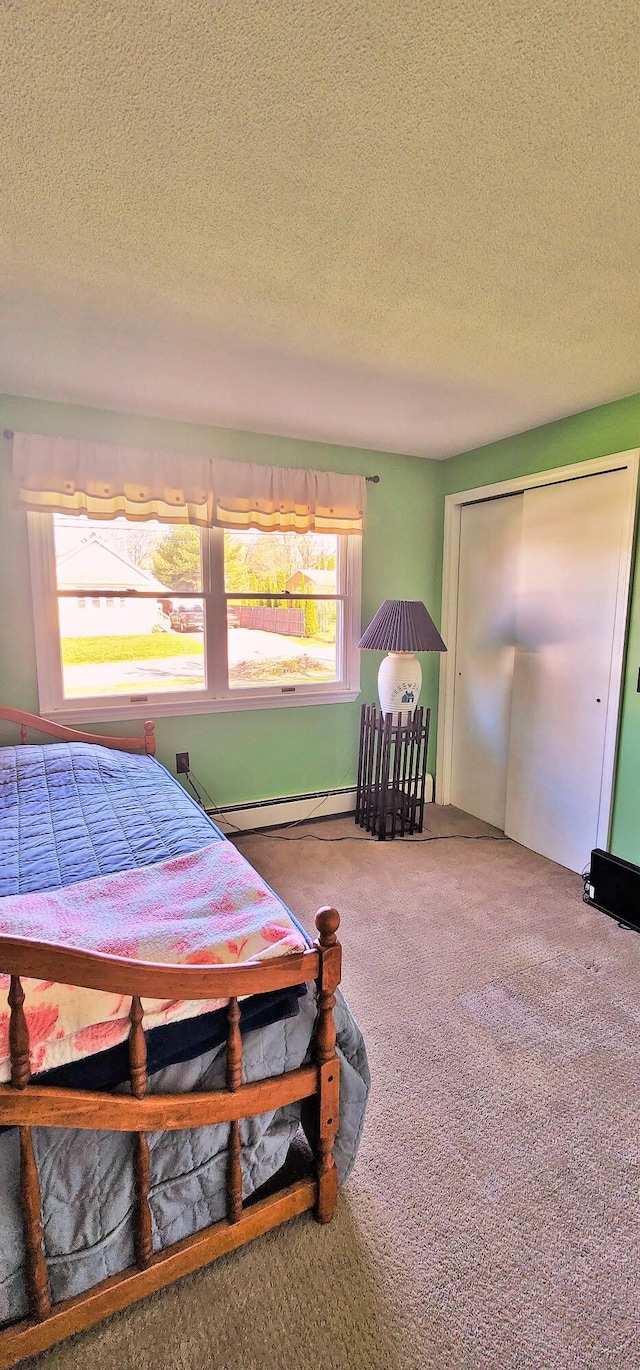 bedroom with carpet floors, a textured ceiling, a baseboard radiator, and a closet