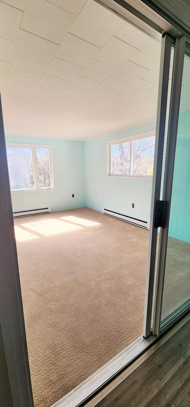 carpeted empty room with baseboard heating and a baseboard radiator