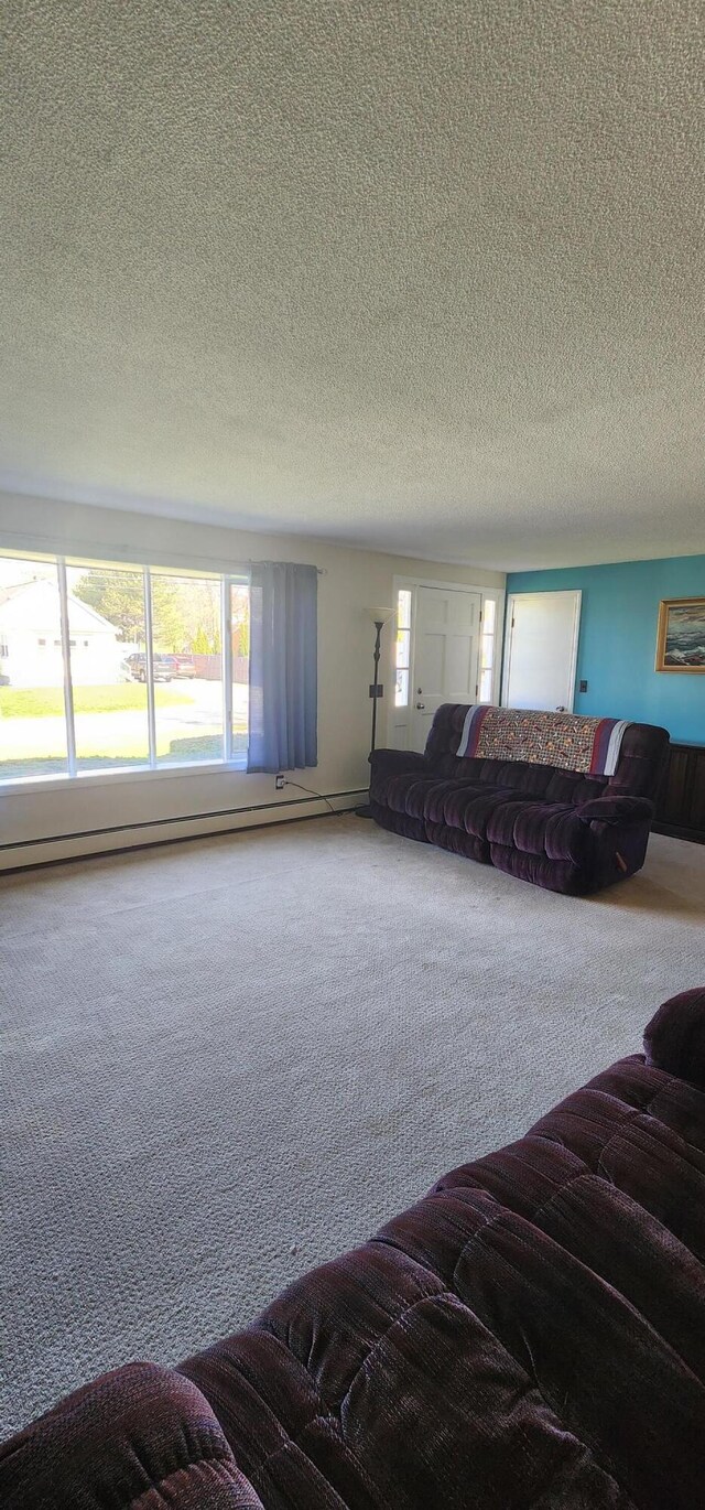 carpeted living room with a textured ceiling and a baseboard heating unit