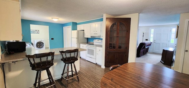 400 Birch St, Bangor, ME 04401 - kitchen featuring white appliances, washer / dryer, a peninsula, white cabinetry, and a breakfast bar area