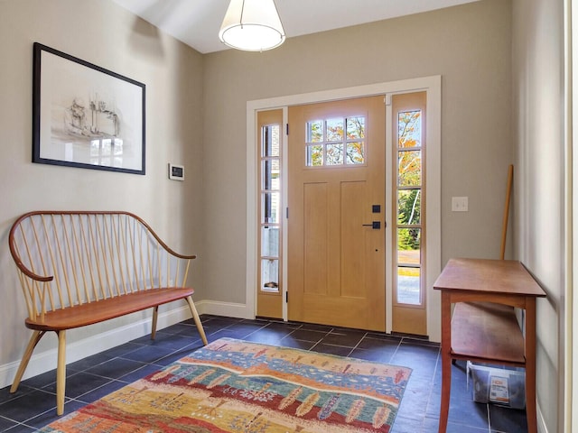 entryway with baseboards and dark tile patterned floors