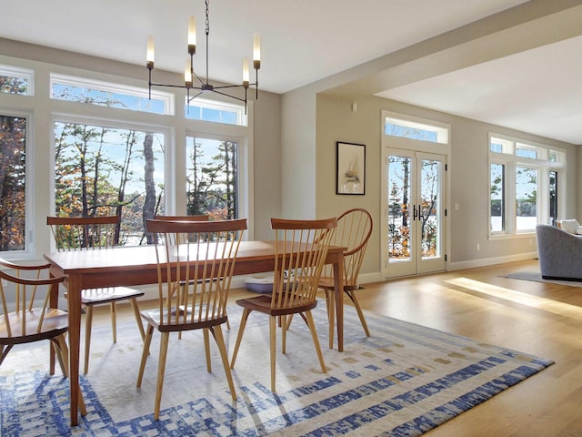 dining area with a chandelier, wood finished floors, baseboards, and french doors