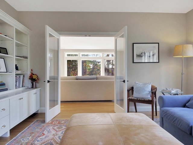living area featuring french doors, wood finished floors, and baseboards
