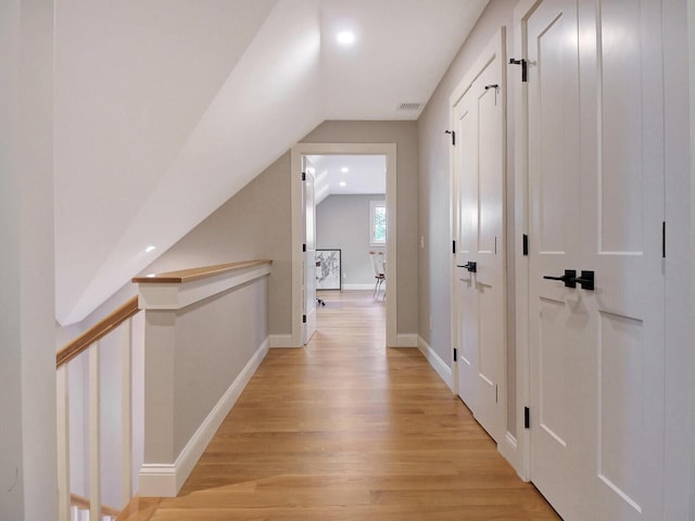 corridor with vaulted ceiling, light wood-style flooring, baseboards, and recessed lighting