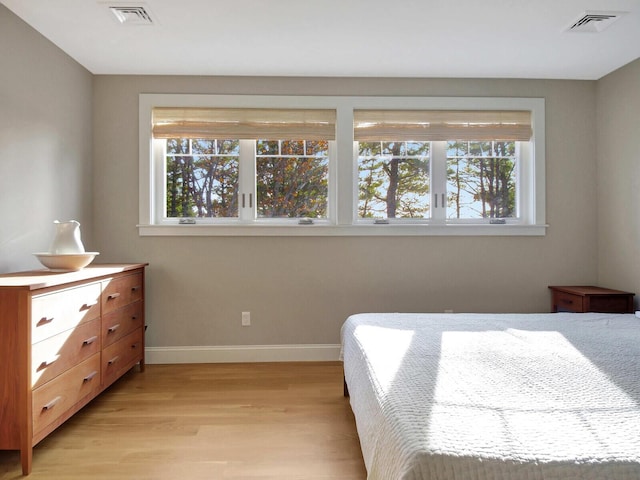 bedroom with light wood-style floors, multiple windows, and baseboards