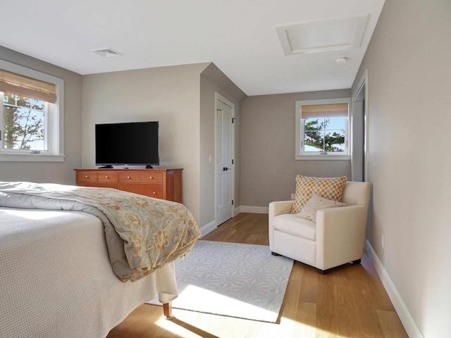 bedroom with wood finished floors, baseboards, and attic access